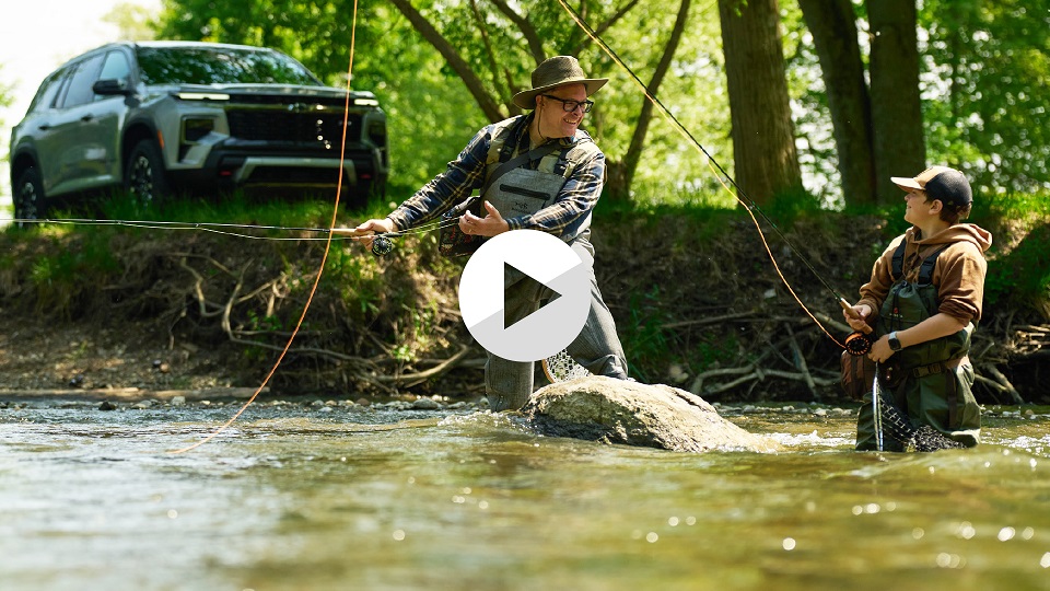 Father and son fly fishing with Chevy Traverse in the bacakground 