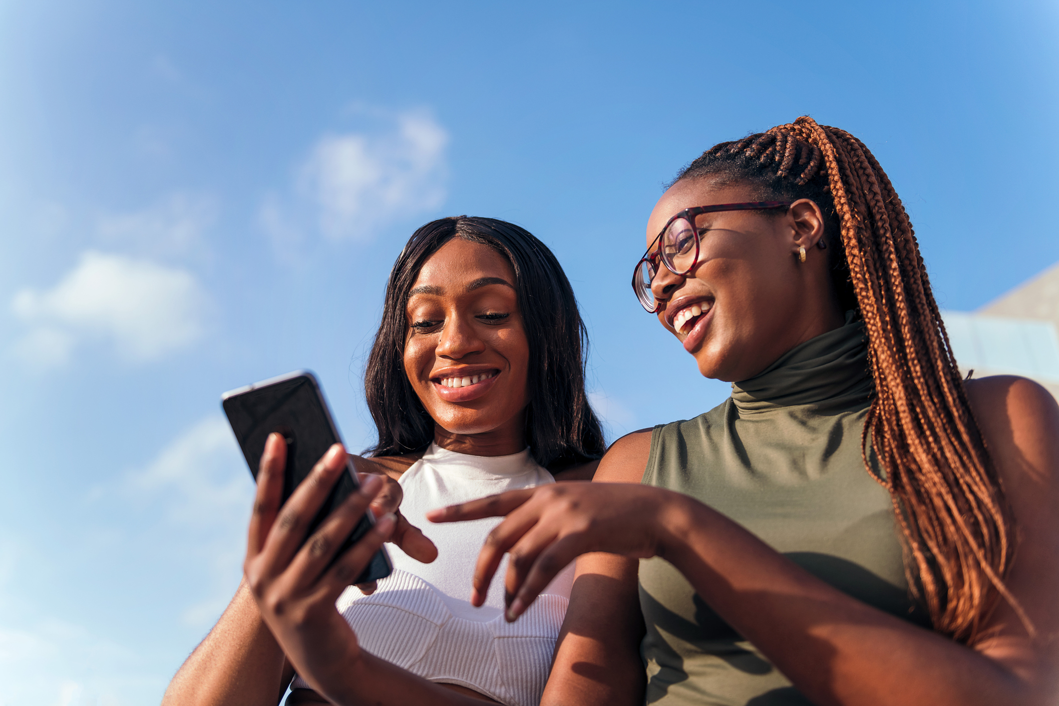 two young african women having fun looking at the cell phone, concept of youth and communication technology, copy space for text