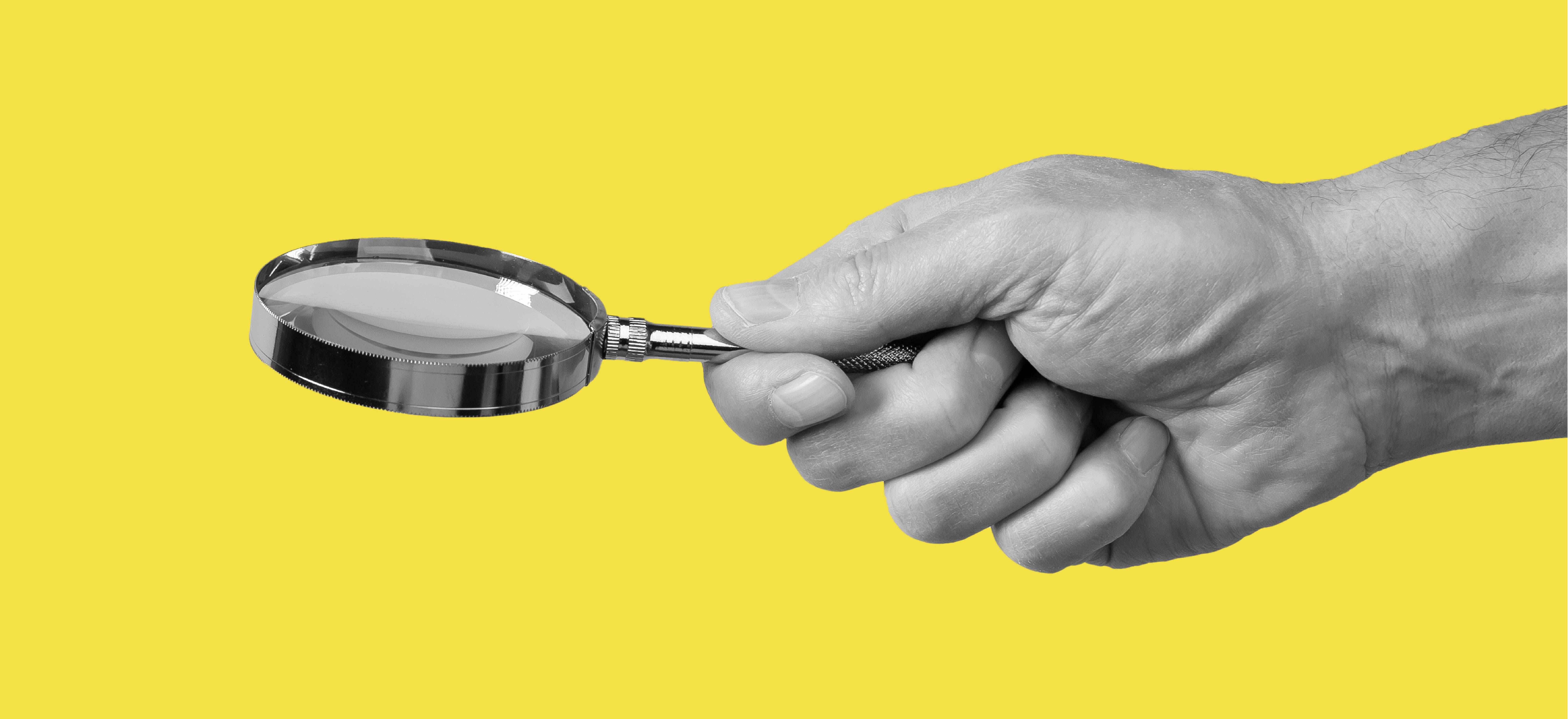 hand holding magnifying glass with yellow background