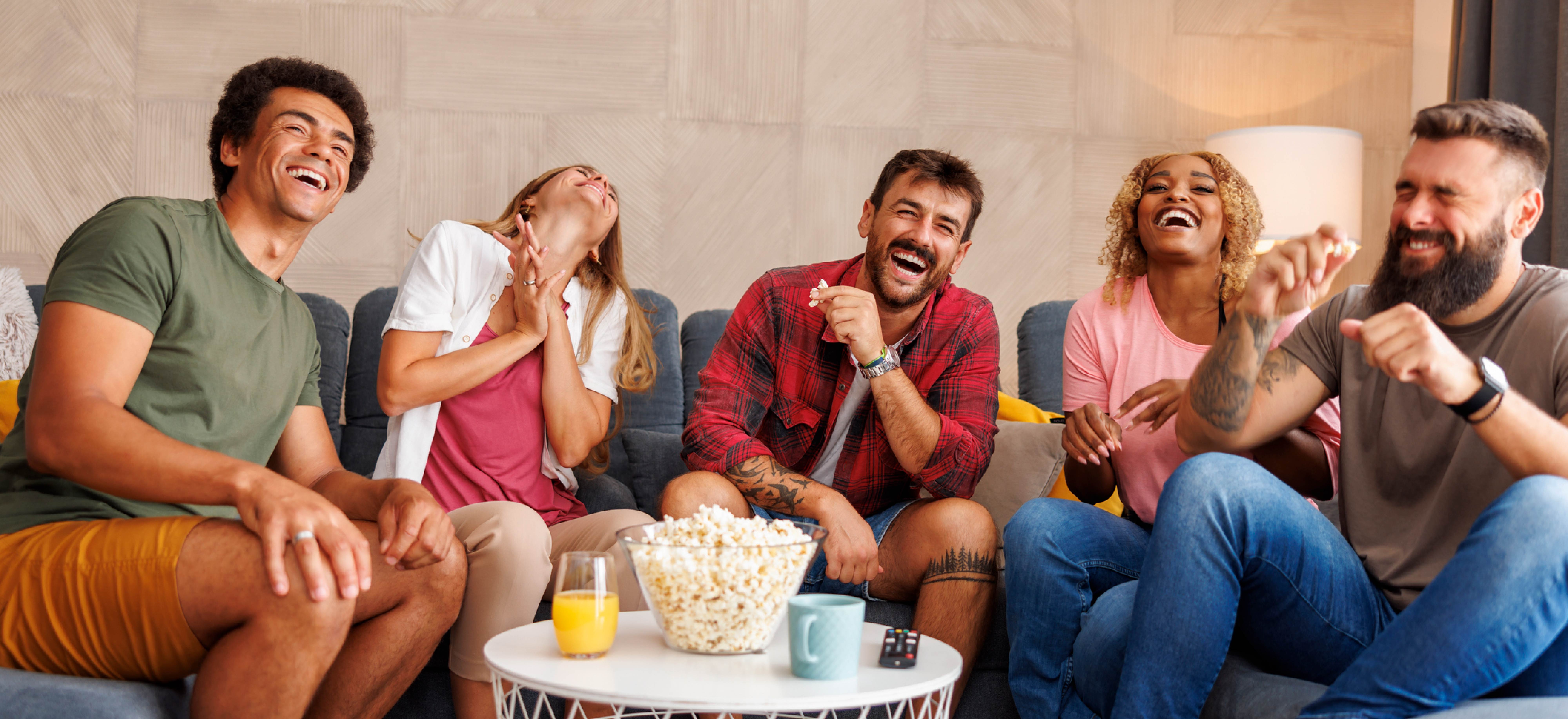 group of friends laughing with popcorn and beverages