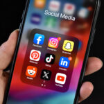 platform-specific messaging - iPhone being held with a social media folder open